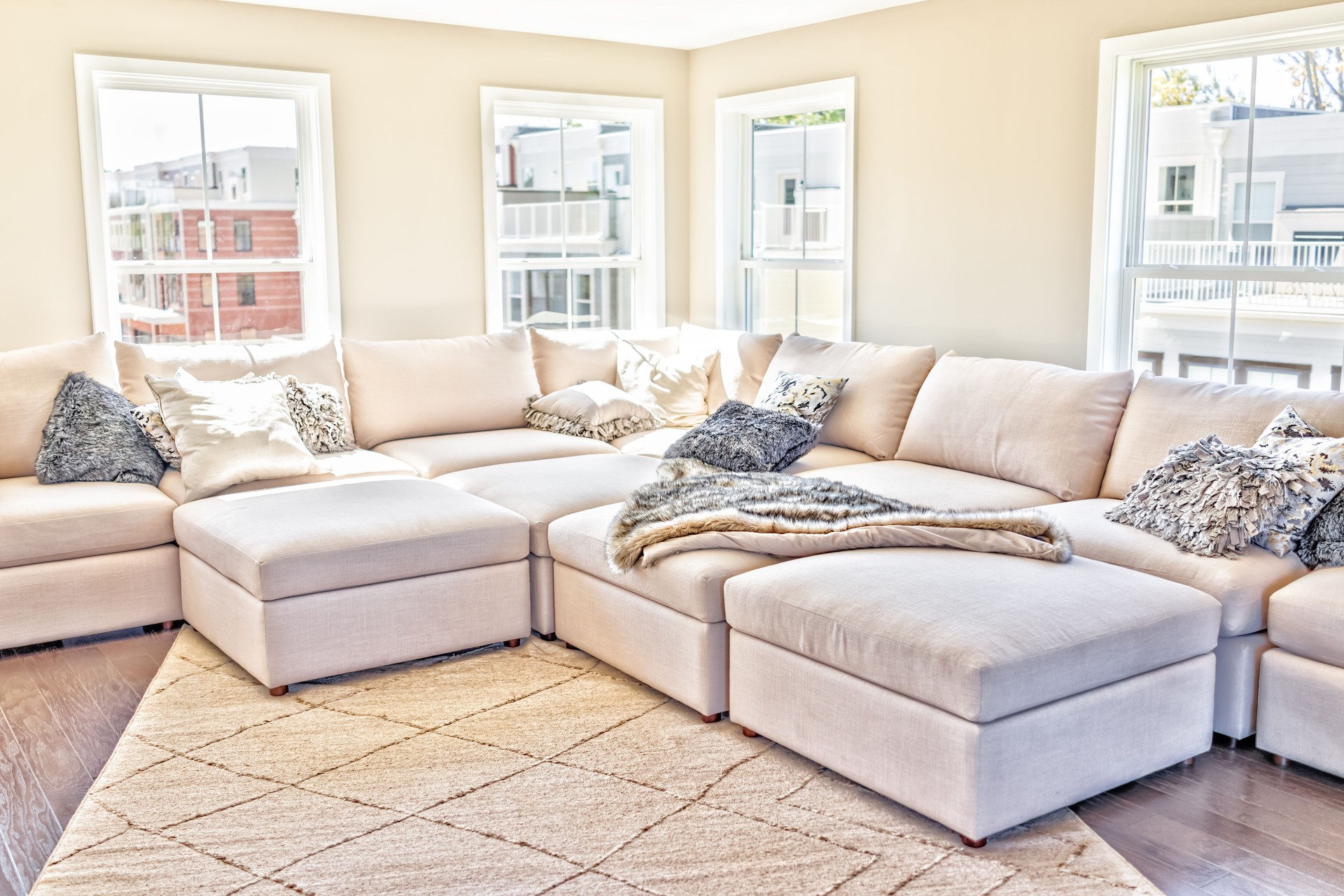 Loft interior space of modern apartment, house or home with staging of large beige, neutral white couches and throw rugs with pillows